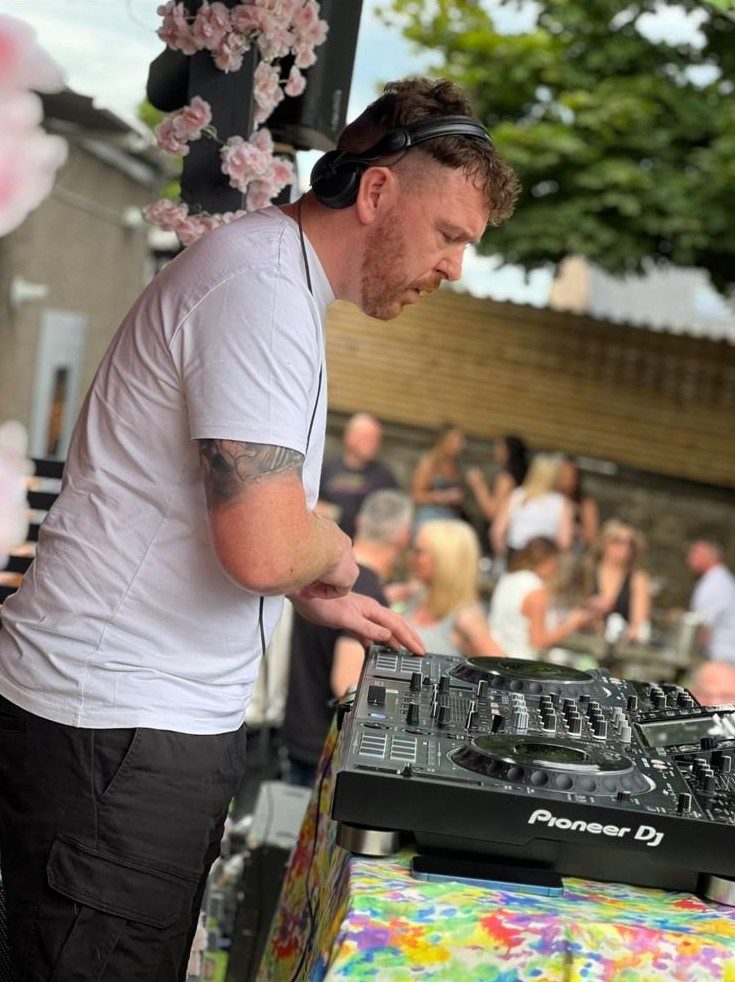 A young DJ mixing on Pioneer decks in front of a crowd