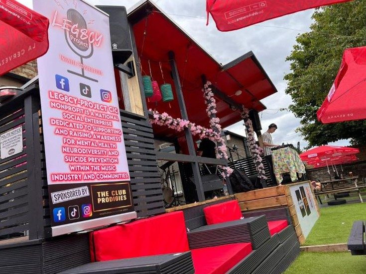 A DJ playing an outdoor Leg8cy Project stage with the branded banner