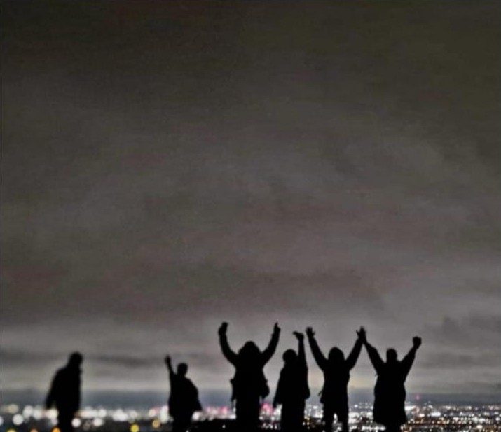 The group on a summit at night with city lights below
