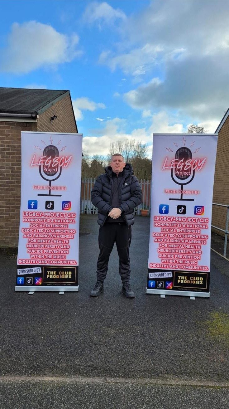 Scott Glover standing between two Leg8cy Project CIC banners